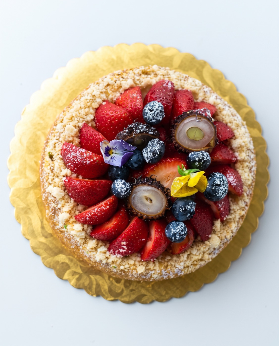 Seasonal strawberry tart with blueberries and powdered sugar