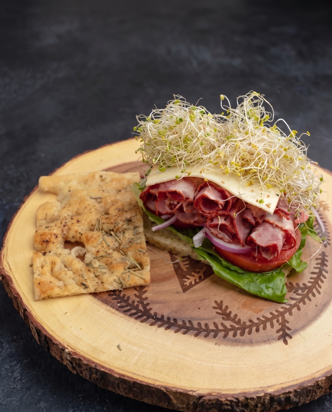 Pastrami sandwich on focaccia with muenster, sprouts and tomato