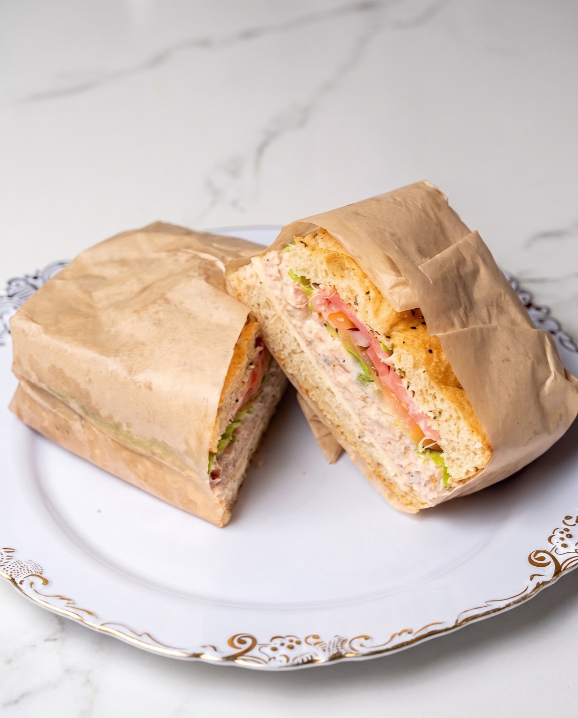 Tuna salad sandwich cut in half, wrapped in butcher paper
